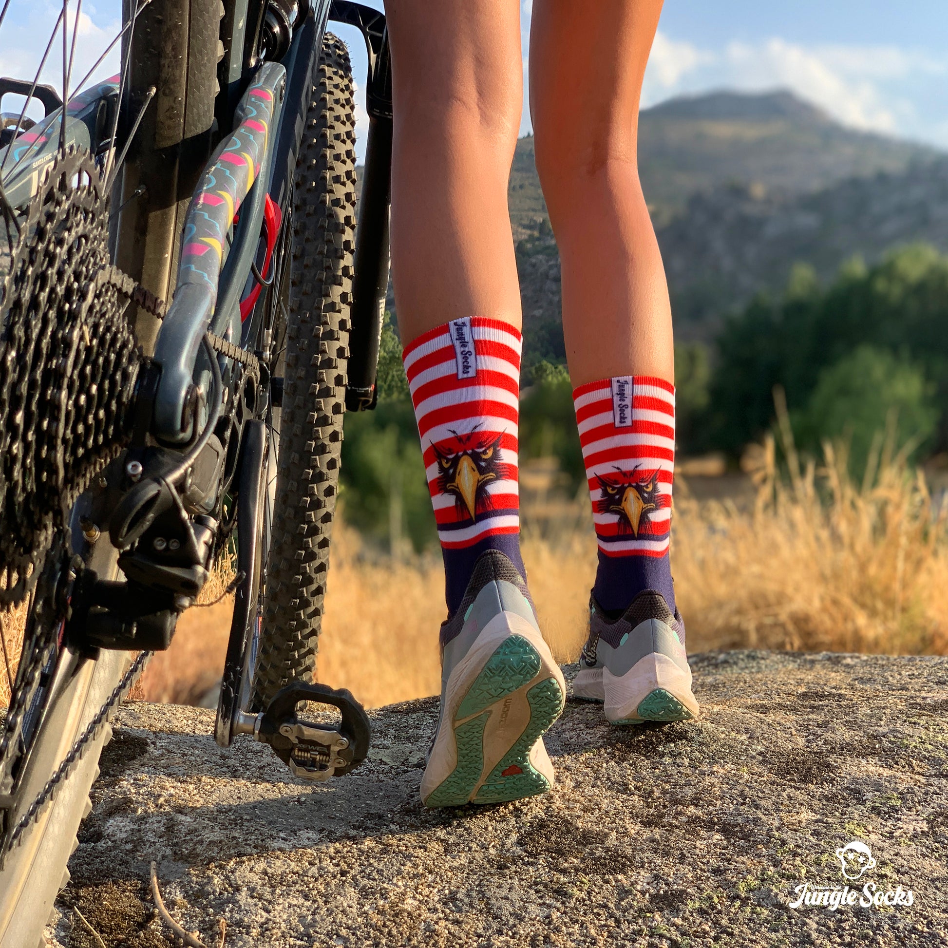 Mujer con calcetines deportivos JungleSocks con la bandera de EEUU en bicicleta de montaña