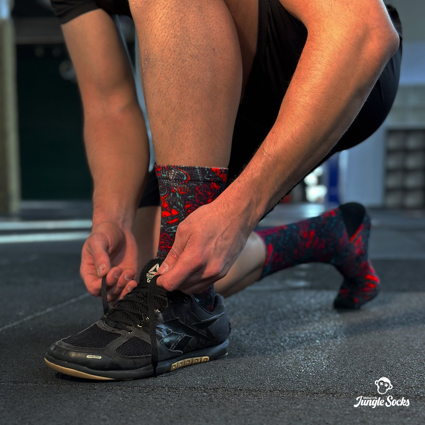 Deportista profesional de crossfit atándose los cordones de las zapatillas con calcetines de Crossfit JungleSocks Tattoo